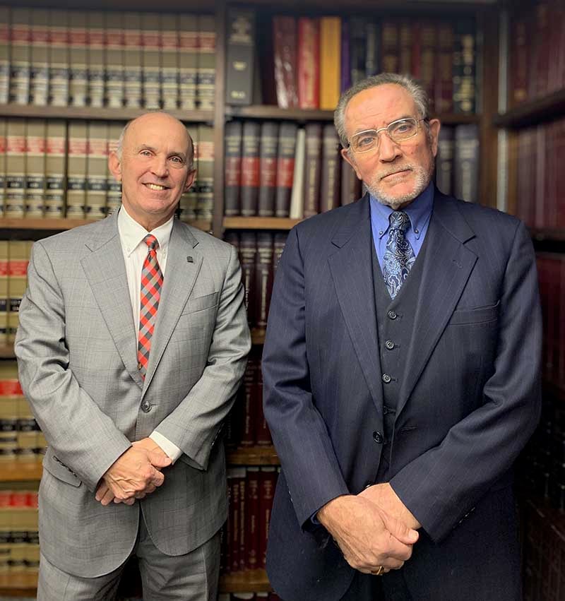 Both attorneys standing in front of law books